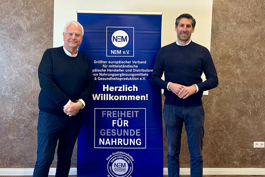 Bild von Dr. Grosselfinger und Manfred Scheffler vor einem Plakat des NEM Verbandes.